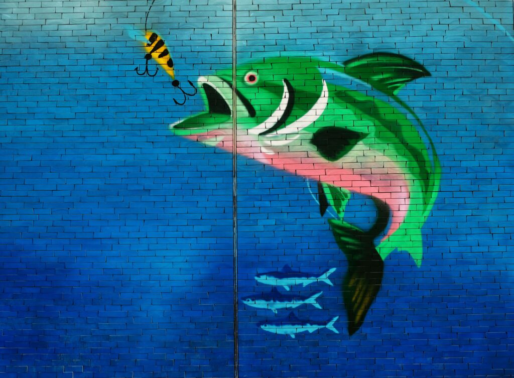 mural of a fish biting a lure on a brick wall